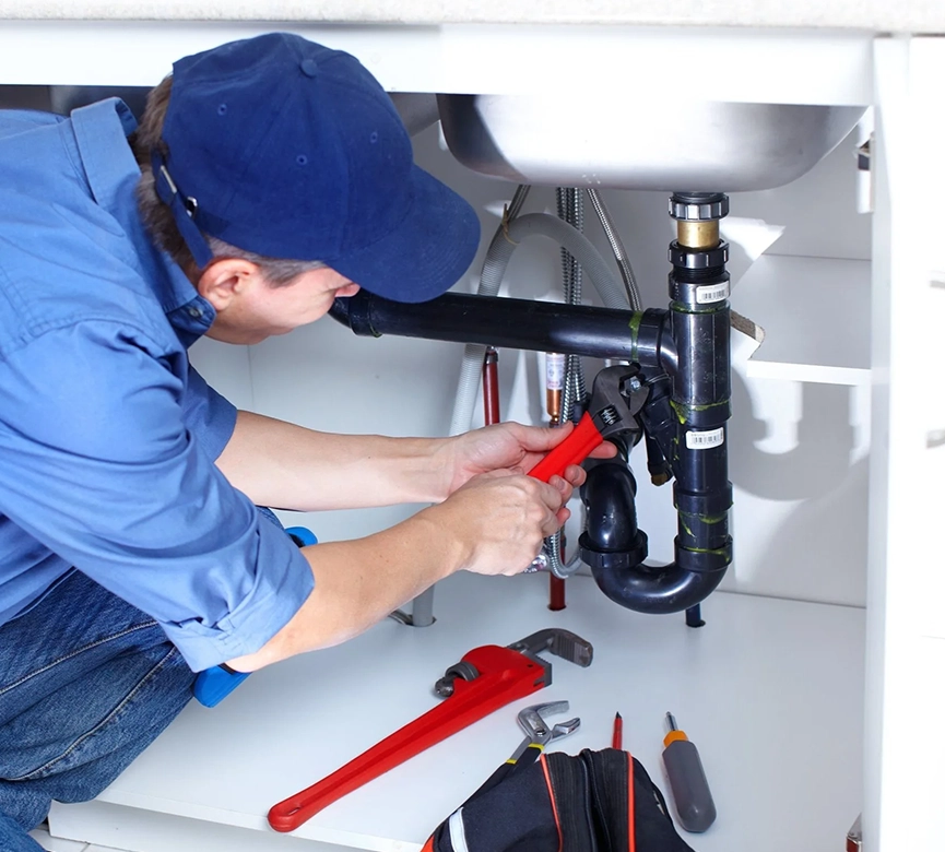 Plumber Fixing Pipes Under Sink with Red Wrench, Plumbing Repair Services