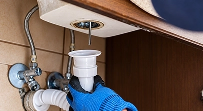 Worker Fixing Sink Pipes in a Bathroom with Plumbing Repair Tools